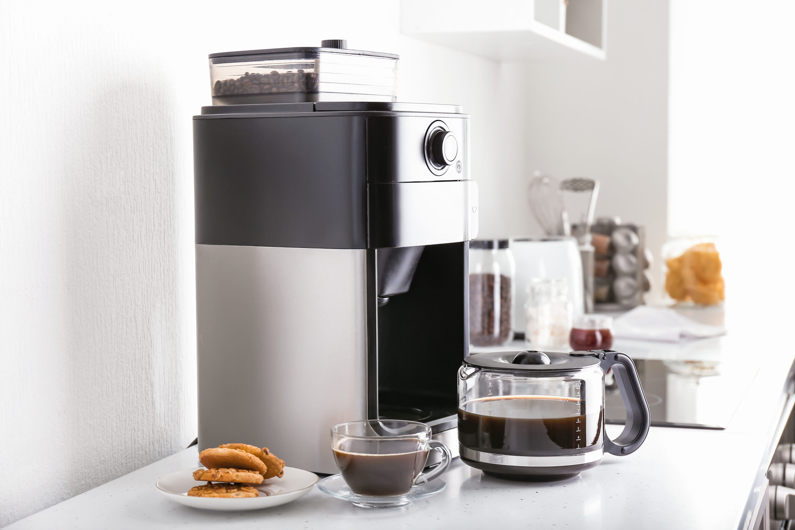 Modern drip coffee maker and coffee cup on kitchen table